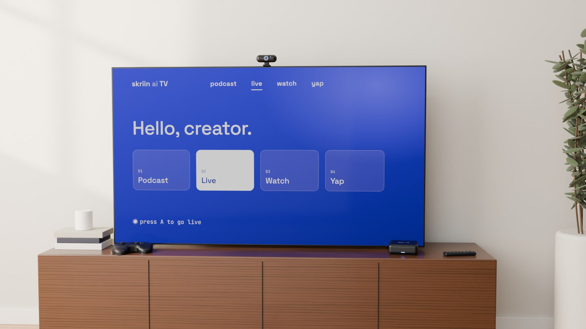 A TV on a walnut console showing the skriin home screen, with the camera clipped on top and the skriin ai TV box beside it